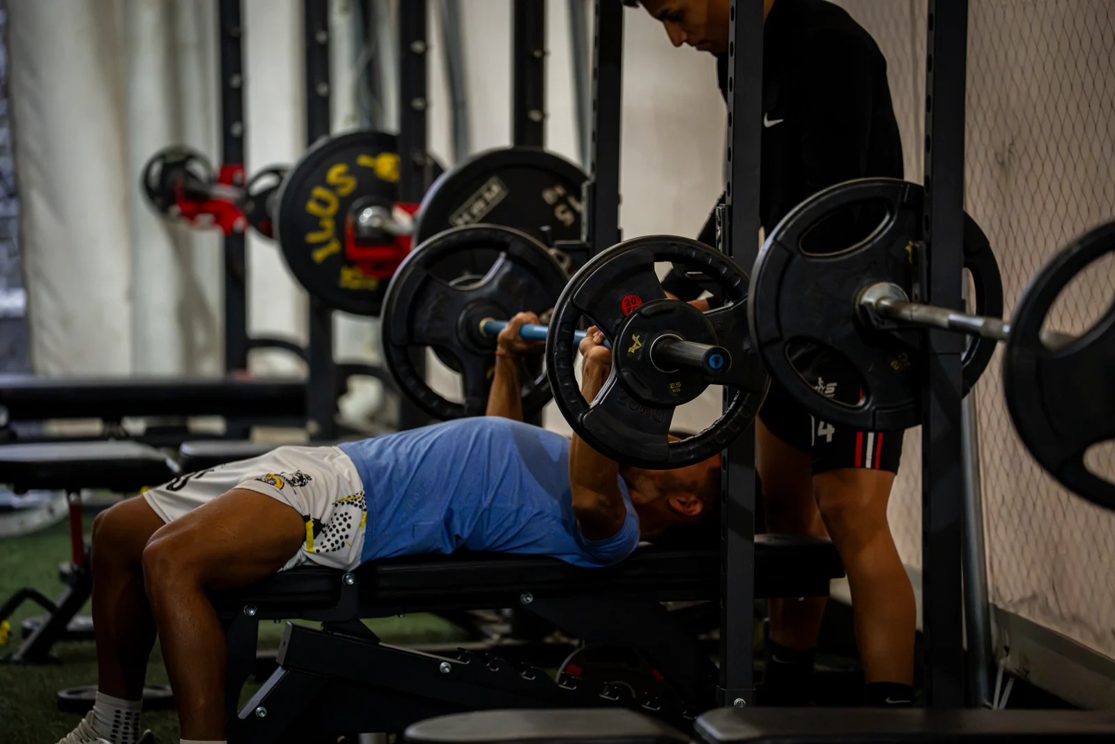 Trabajo de fuerza con barra y acompañamiento durante una sesión de gimnasio de 90+